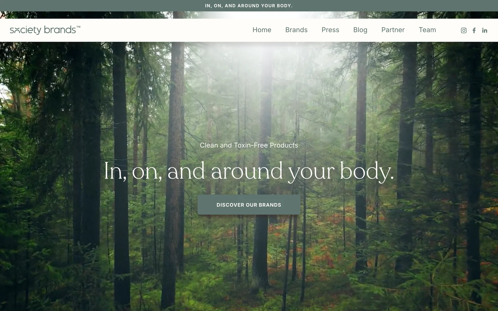 Society Brands homepage with a forest photograph, the line In, on, and around your body, and a Discover our brands button